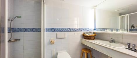 Et badeværelse med brusebad, toilet og håndvask.
