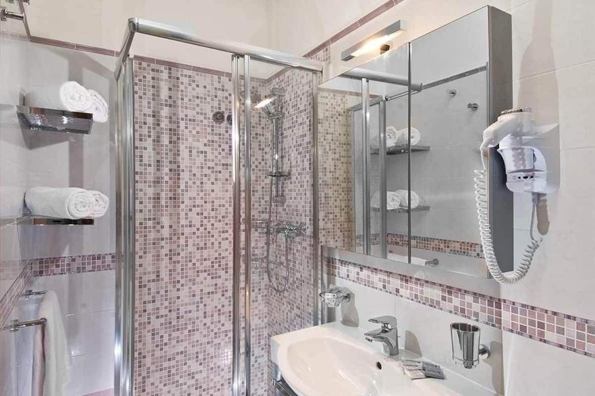 A modern bathroom with a glass-enclosed shower, a white sink, and a large mirror.