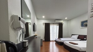 A hotel room with a desk, two beds, a mirror, a phone, and an air conditioning unit. - Bordin Hotel (Ubon Ratchathani)