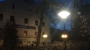Een gebouw met een bord waarop staat 'GASTHOF Flamminger' en een kerstboom met lichtjes.