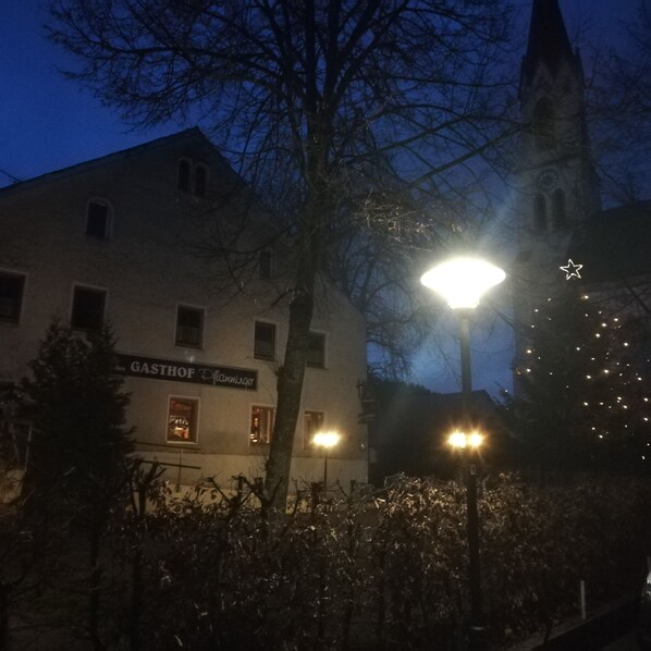 Un bâtiment sur lequel on peut lire l’inscription « GASTHOF Flamminger », et un sapin de Noël illuminé.