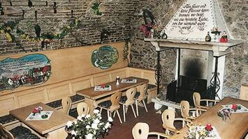 Un restaurante con mesas y sillas de madera, una pared de ladrillo con adornos y una chimenea.