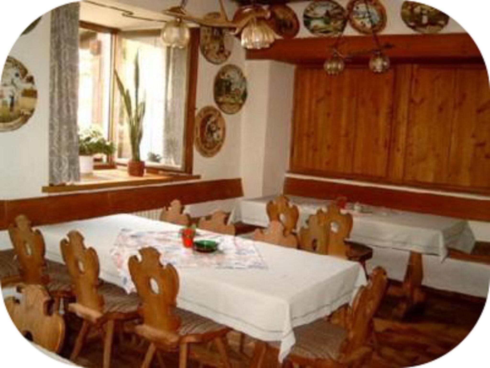 Un comedor con sillas y mesas de madera, techo de madera y adornos en las paredes.