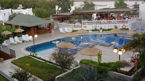 Un hotel con piscina, sillones de descanso y sombrillas.