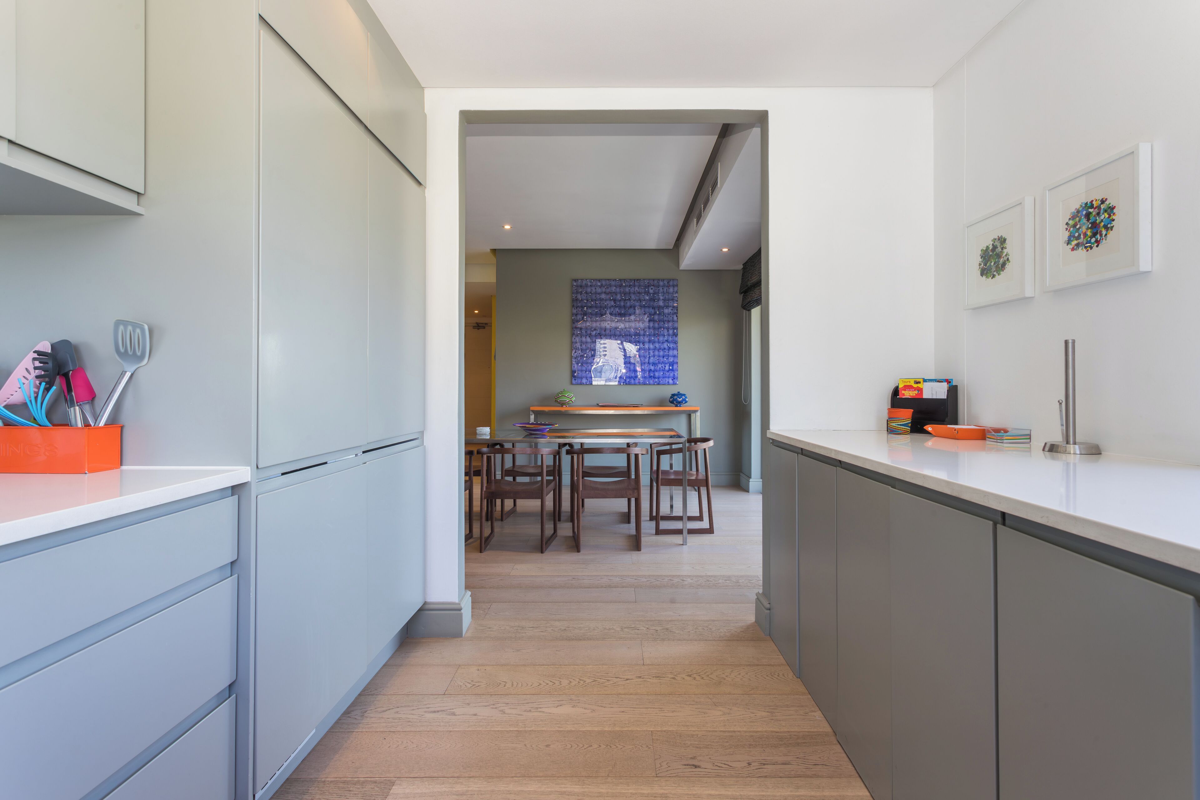 Una cocina moderna con armarios grises, una mesa de comedor de madera y un salpicadero azul.