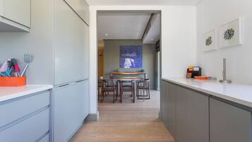 Una cocina moderna con armarios grises, una mesa de comedor de madera y un salpicadero azul.
