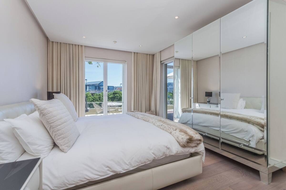 Une chambre d’hôtel moderne dotée d’un grand lit, d’une paroi en verre et offrant une vue sur l’extérieur.