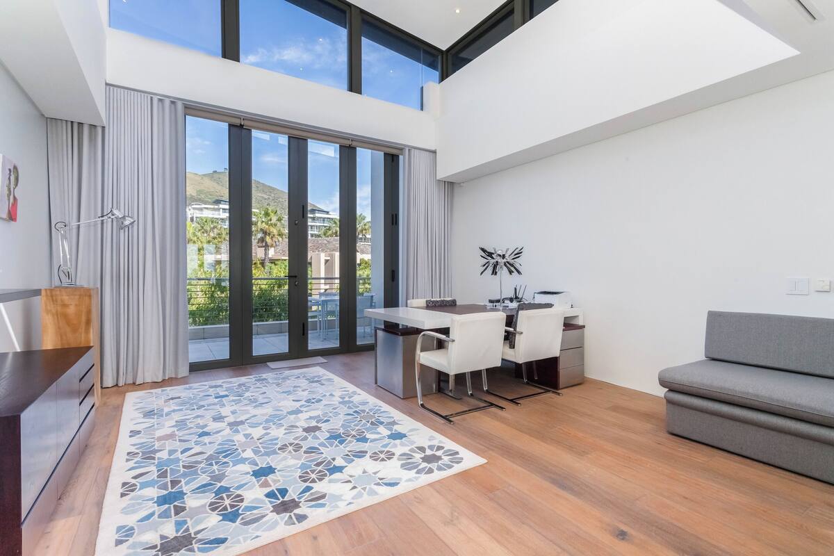 Un intérieur moderne comprenant un coin repas, un canapé et une vue sur une colline.