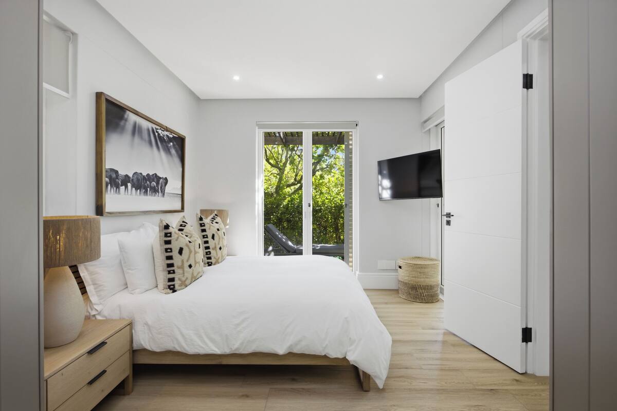 Une chambre à coucher avec un lit, une télévision, un tableau et une fenêtre.
