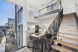 Un interior moderno con escalera, ventanas amplias y balcón.