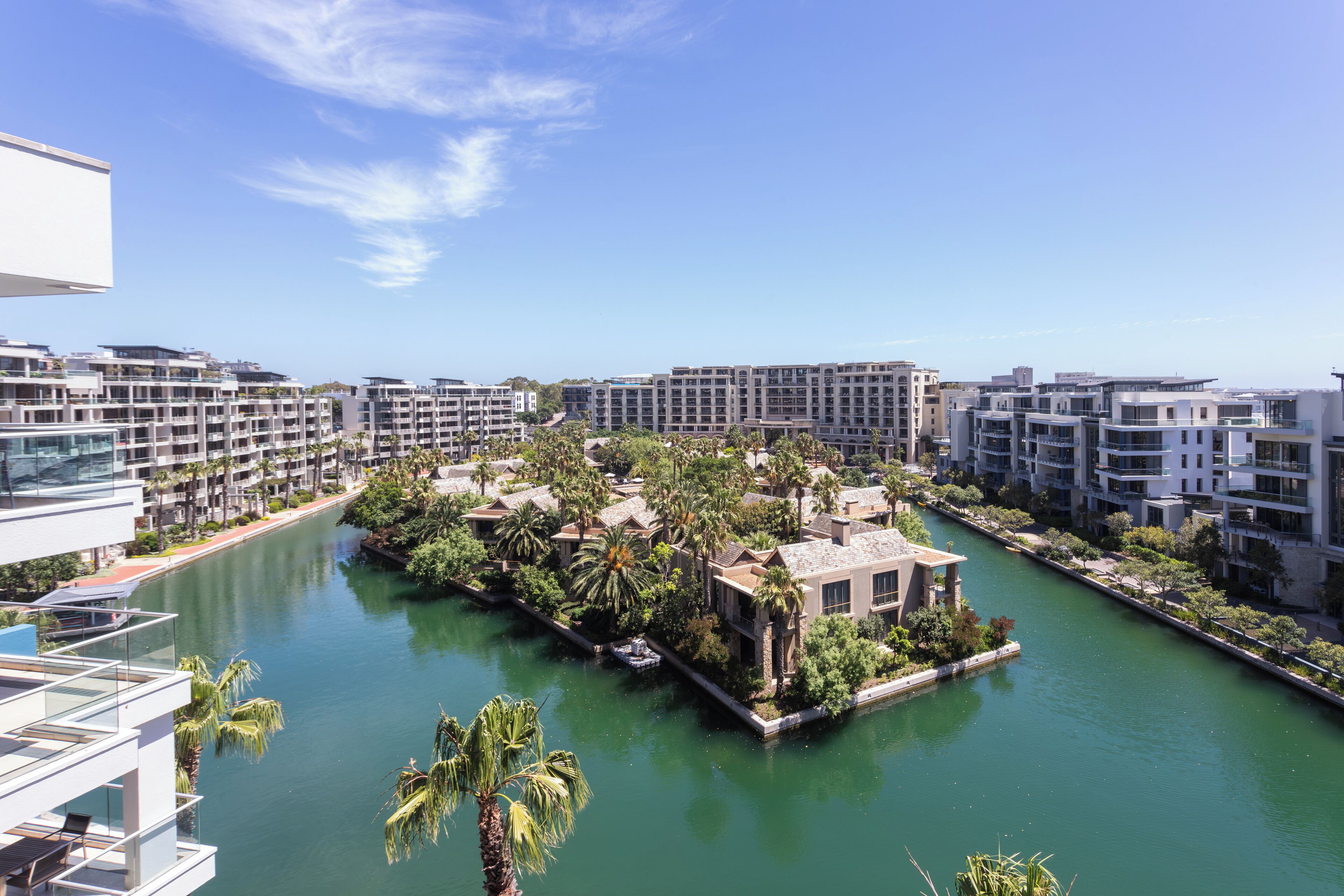 A modern hotel with a river running through its courtyard, surrounded by lush greenery and contemporary architecture.