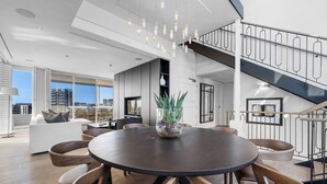 Un espace de salle à manger moderne avec une table ronde, des chaises en bois et des luminaires suspendus.