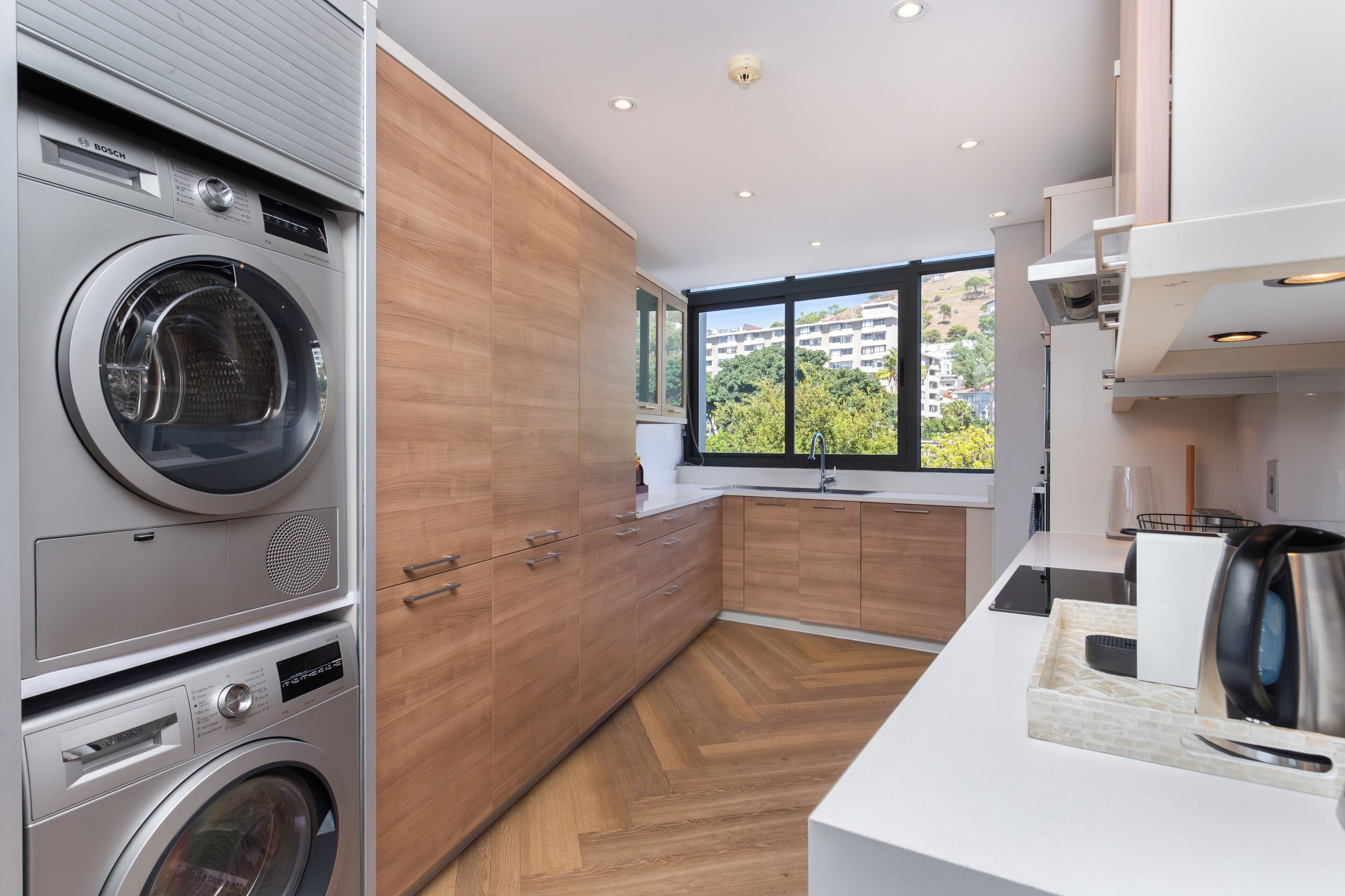 A modern kitchen with built-in appliances, a large window, and a view of the city.