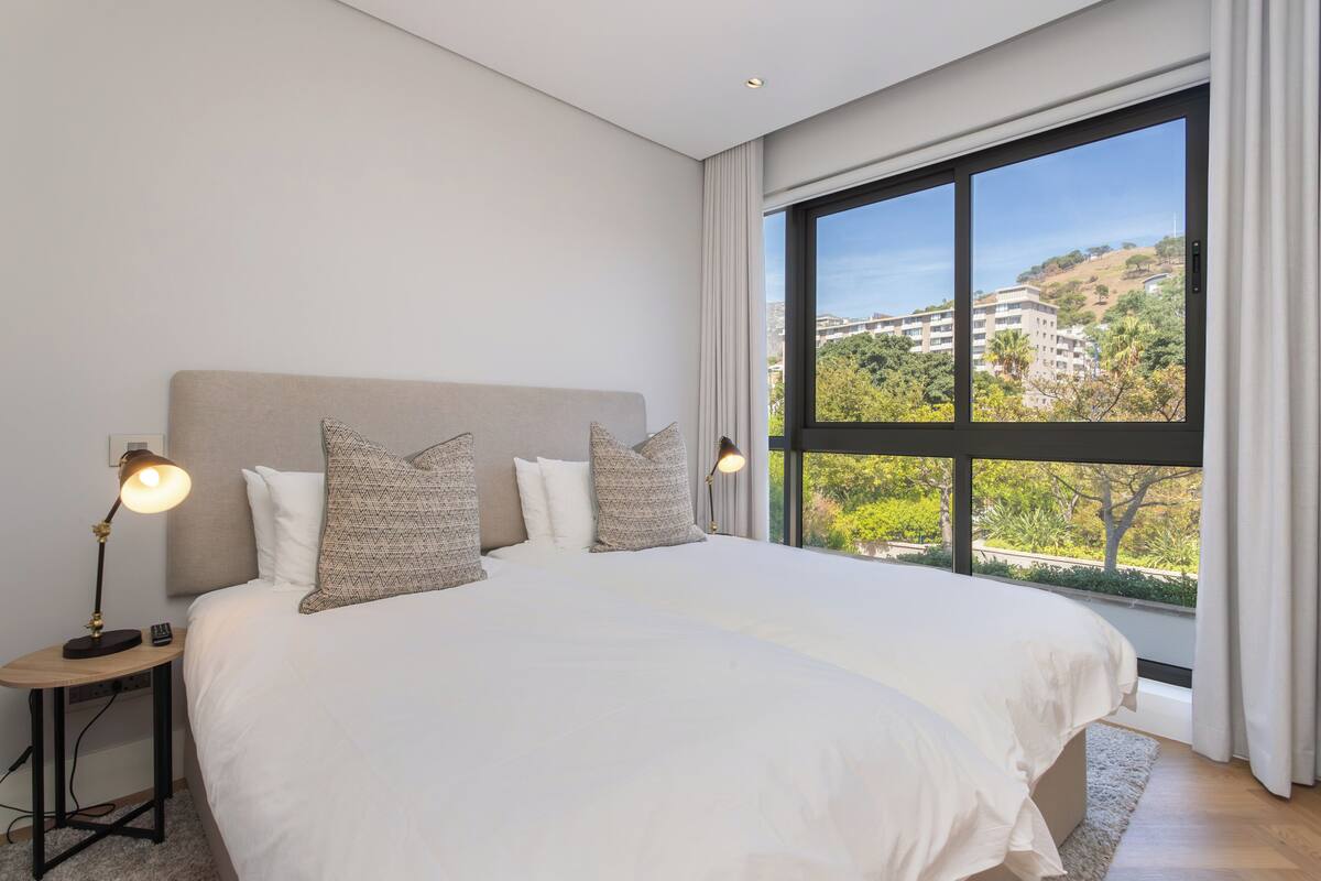 Une chambre avec un grand lit, deux lampes de chevet et une vue sur une colline.