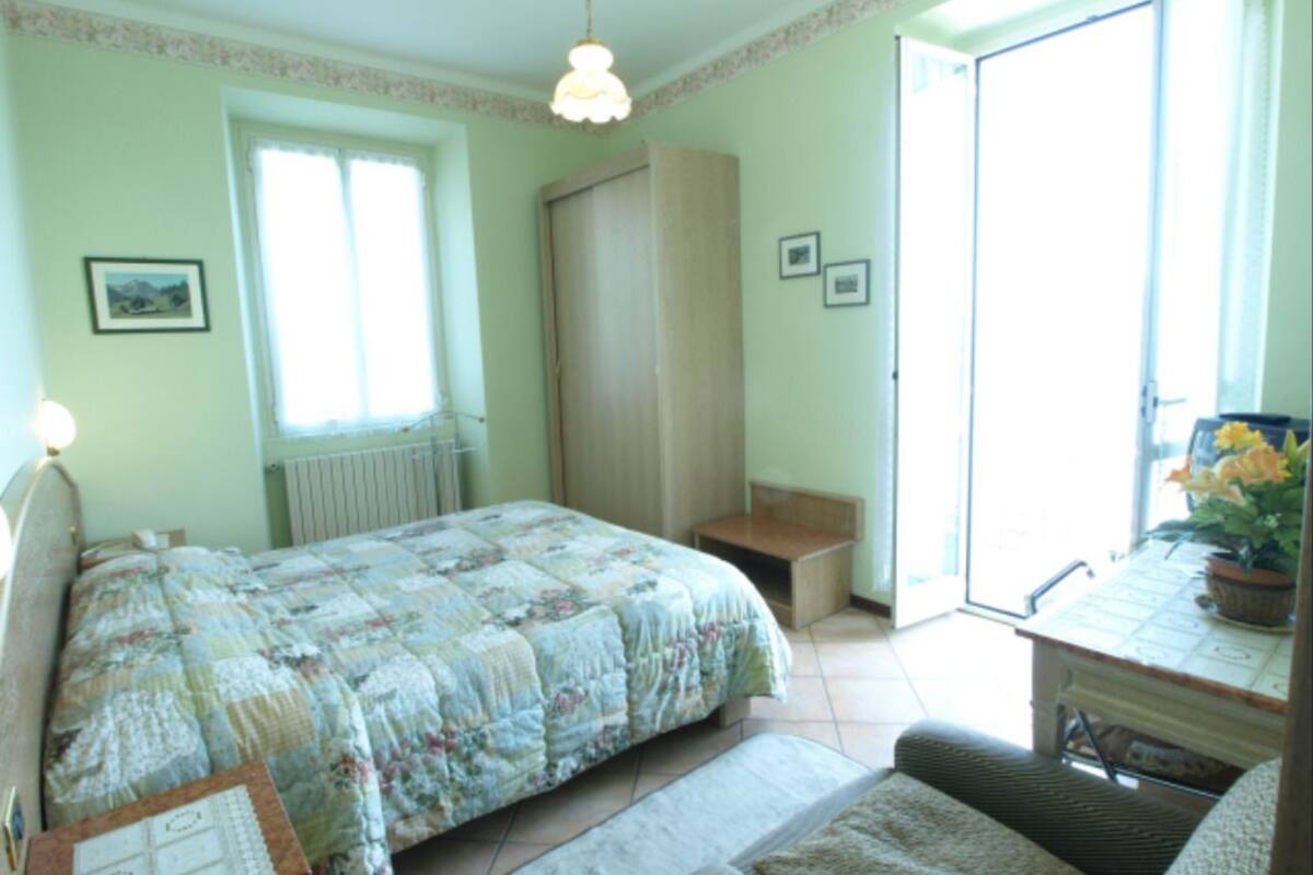 Une chambre à coucher avec un lit, un bureau, une chaise, un radiateur et une fenêtre.