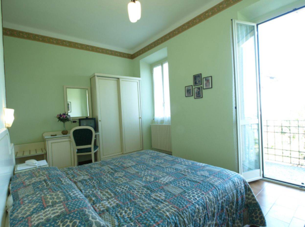 Un dormitorio con cama, escritorio, silla, radiador, ventana y puerta.