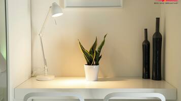 Una scrivania moderna e minimalista con una lampada bianca, una pianta in vaso e due vasi neri.