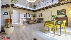 A spacious living area with a high ceiling, a dining table with yellow chairs, a sofa set, and a staircase leading to an upper level. - B&B Cubbaita (Palermo)
