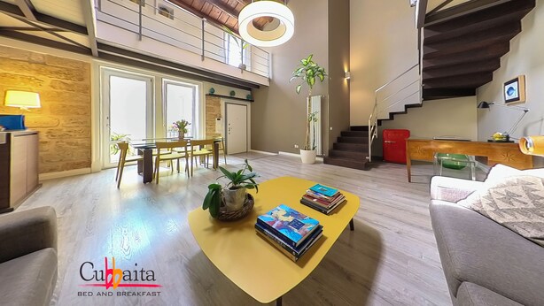 A spacious living area with a high ceiling, a staircase, and a dining area. - B&B Cubbaita (Palermo)