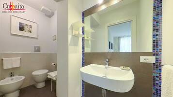 A modern bathroom with a bidet, toilet, and sink.