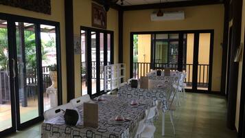 A dining area with long tables, chairs, and a ceiling fan.