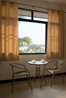 A room with a window, two chairs, and a small table with cups.