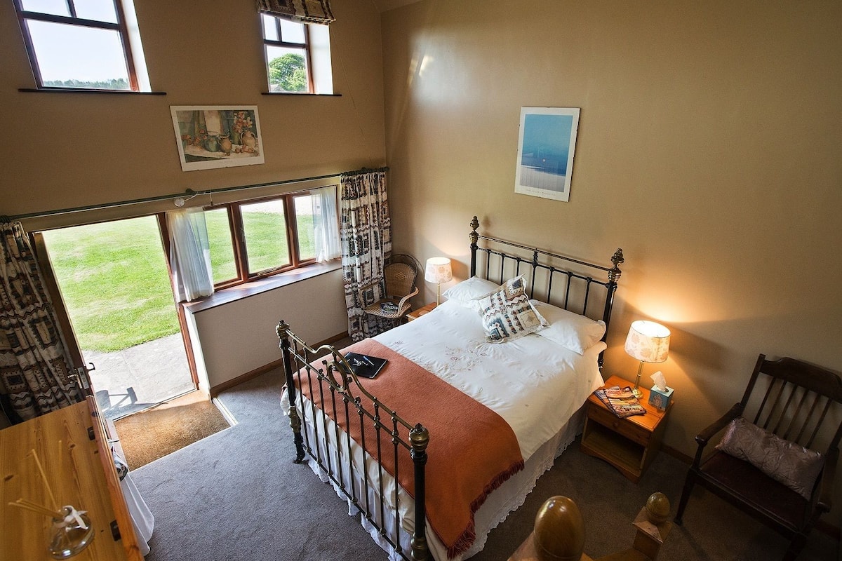 A bedroom with a bed, bedside tables, a chair, and a window with curtains.