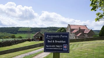 Experience a Bed & Breakfast in a rural setting surrounded by lush greenery and a stone wall.
