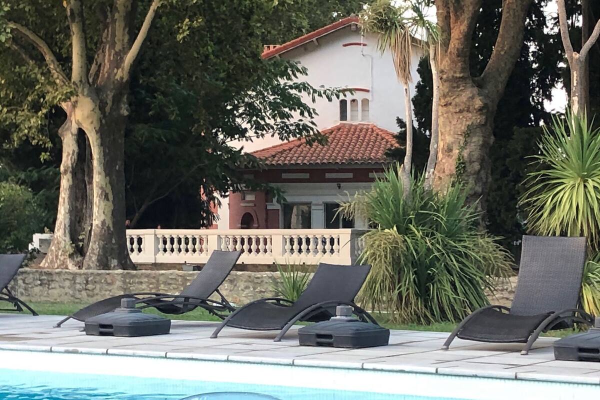 Ein Poolbereich mit Liegestühlen und ein Gebäude im Hintergrund mit roten Ziegeln.