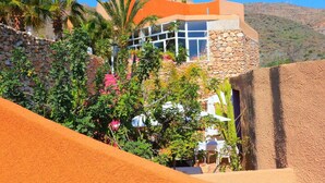 Un edificio moderno con fachada de piedra, ventanas amplias y una estructura naranja destacada en el techo.