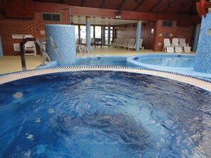 Una piscina cubierta, una piscina al aire libre, sombrillas, tumbonas