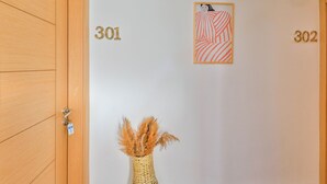 A hallway with doors numbered 301 and 302, a framed artwork, and a vase with dried plants. - Bahar Pansiyon (Kas)