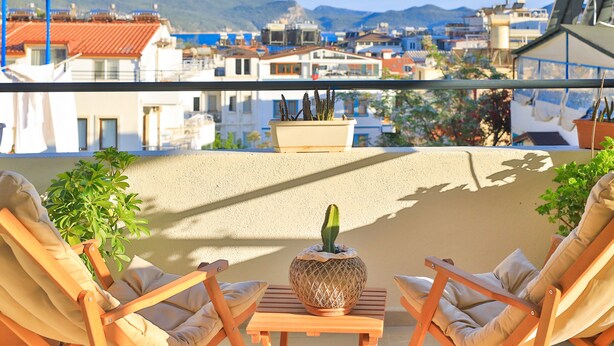 A balcony with two beige lounge chairs, a small table, and a potted cactus. - Bahar Pansiyon (Kas)
