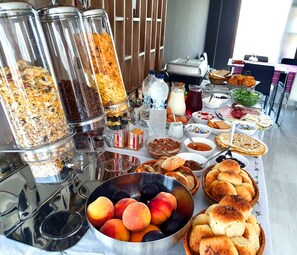 Une table de buffet proposant une variété d’aliments, notamment des fruits, des pâtisseries et des boissons.