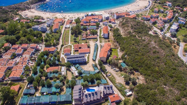 An aerial view of a coastal resort with multiple buildings, a beach, and a swimming pool. - Hotel Palladium Sithonia (Sithonia)