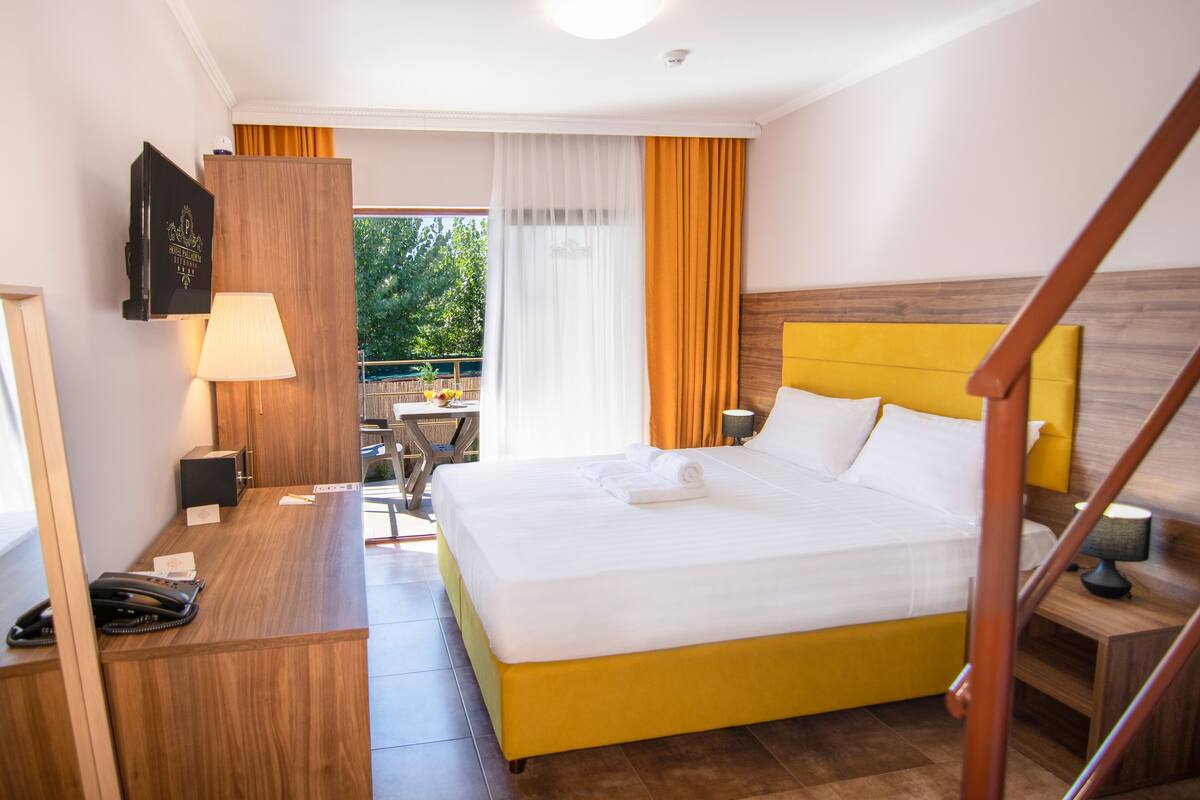 A hotel room with a bed, a desk, a telephone, and a window with curtains.