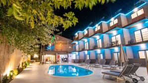 A pool area with lounge chairs and a building with blue lighting. - Hotel Palladium Sithonia (Sithonia)