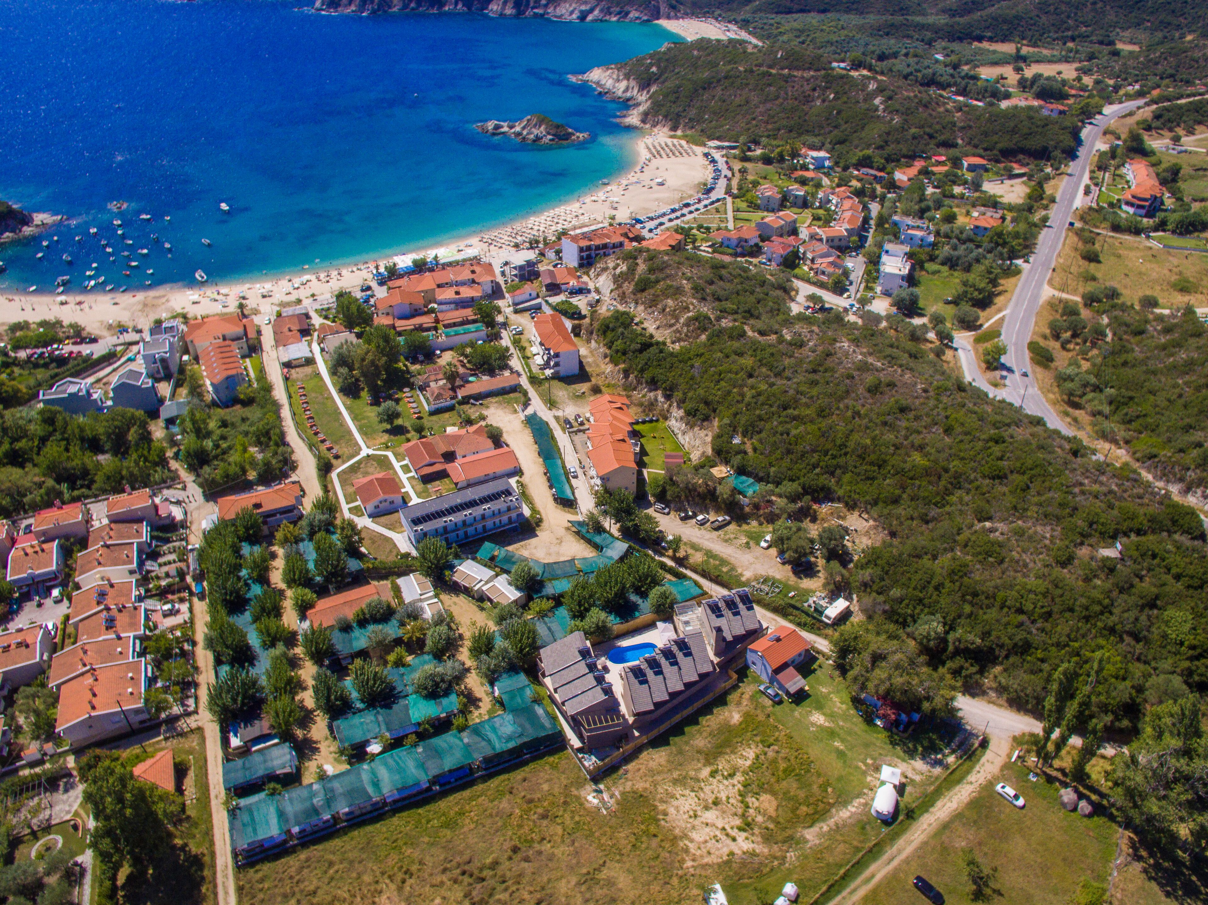 An aerial view of a coastal resort with beach access, multiple buildings, and a swimming pool area.