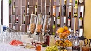 A buffet table with various food items, beverages, and a wine rack in the background. - Hotel Palladium Sithonia (Sithonia)