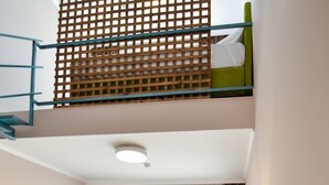 A hotel room with a bed, desk, lamp, and a staircase leading to an upper level. - Hotel Palladium Sithonia (Sithonia)