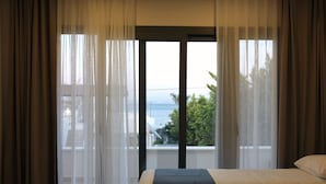Habitación de hotel con dos camas, vista al mar y cortinas translúcidas.
