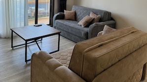 Una sala de estar moderna con un sofá gris, un sofá color beige, una mesita y un ventilador de techo.