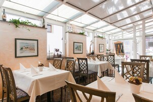 Un restaurante con mesas dispuestas para comer, obras de arte en las paredes y un techo de vidrio.