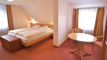 Una habitación de hotel con una cama, una mesita de noche, una silla y una ventana con cortinas.
