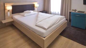 A modern hotel room with a wooden bed, a desk, and a small blue cabinet.