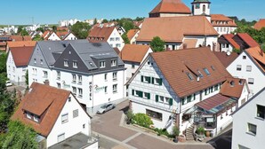 Um hotel com estilo arquitetônico europeu tradicional, com uma torre de igreja bem visível ao fundo.