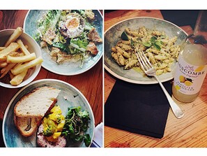 A dining table with four plates of food, a bottle of lemon juice, and a napkin.