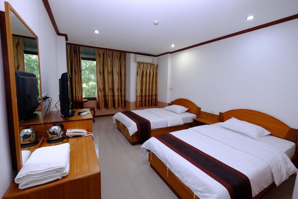 A hotel room with two beds, a wooden desk with a telephone and a kettle, a mirror, and a window with curtains.