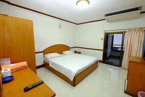 Una habitación de hotel con una cama de madera, una mesita de noche con un control remoto, un rollo de papel higiénico y un cuenco azul.