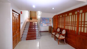 A staircase leading to an upper floor, a reception desk with a map, and a seating area with wooden furniture. - PC Palace Hotel (Sakon Nakhon)